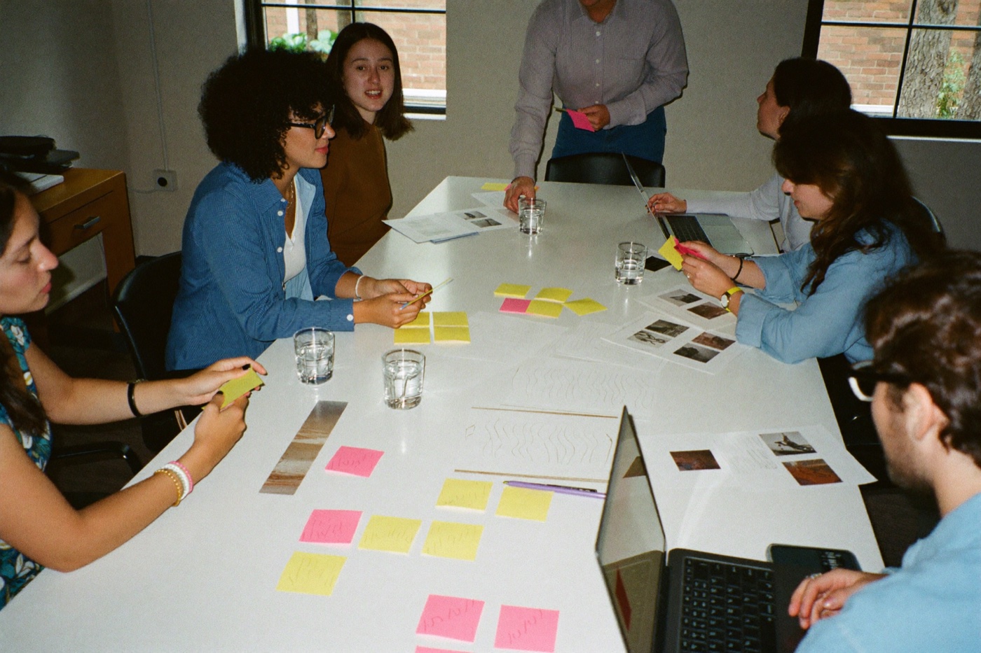 Ideation workshop: the team around a table covered with sticky notes and printed mockups